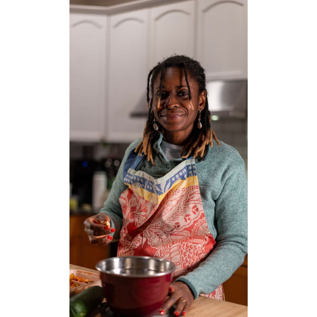 Malika cooking and smiling in her kitchen