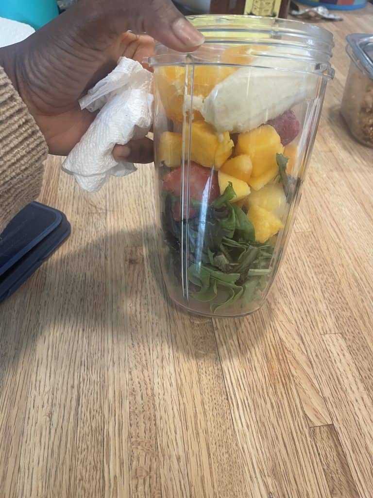 a hand holding a blender full of fruit