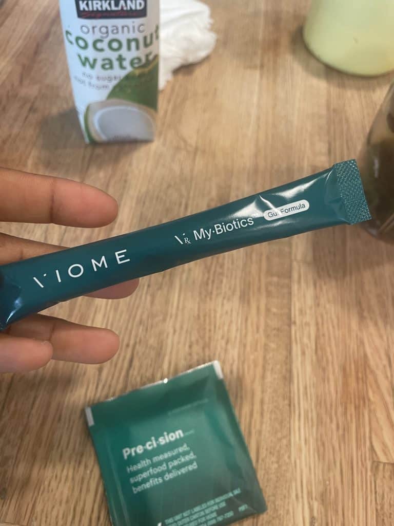 a hand holding a small Viome green tube