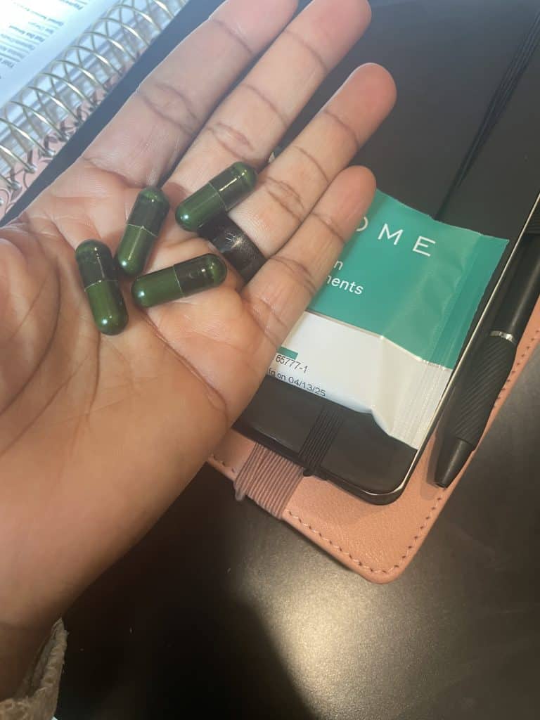a hand holding Viome green capsules