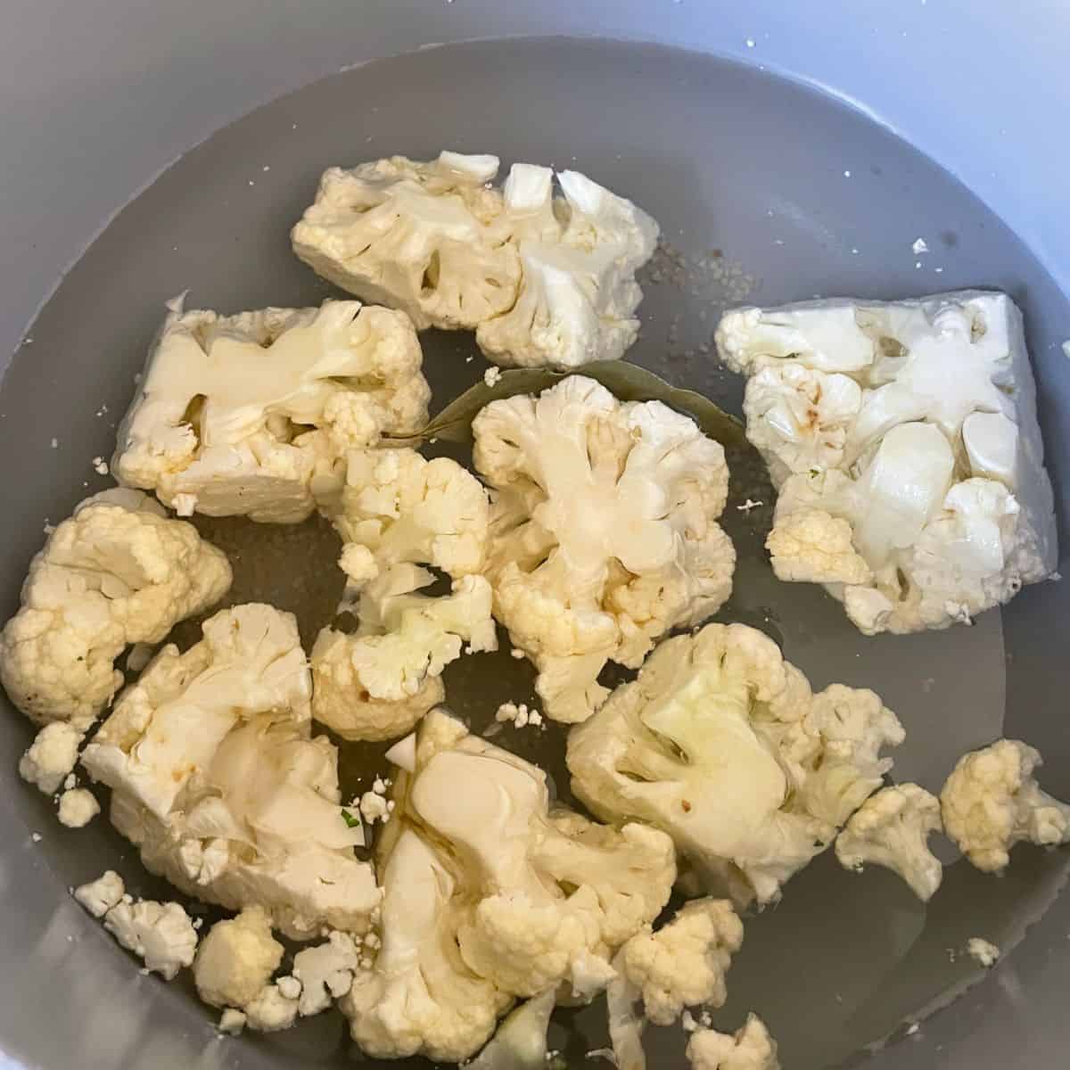 pot of cubes cauliflower in water with bay leaf and some garlic