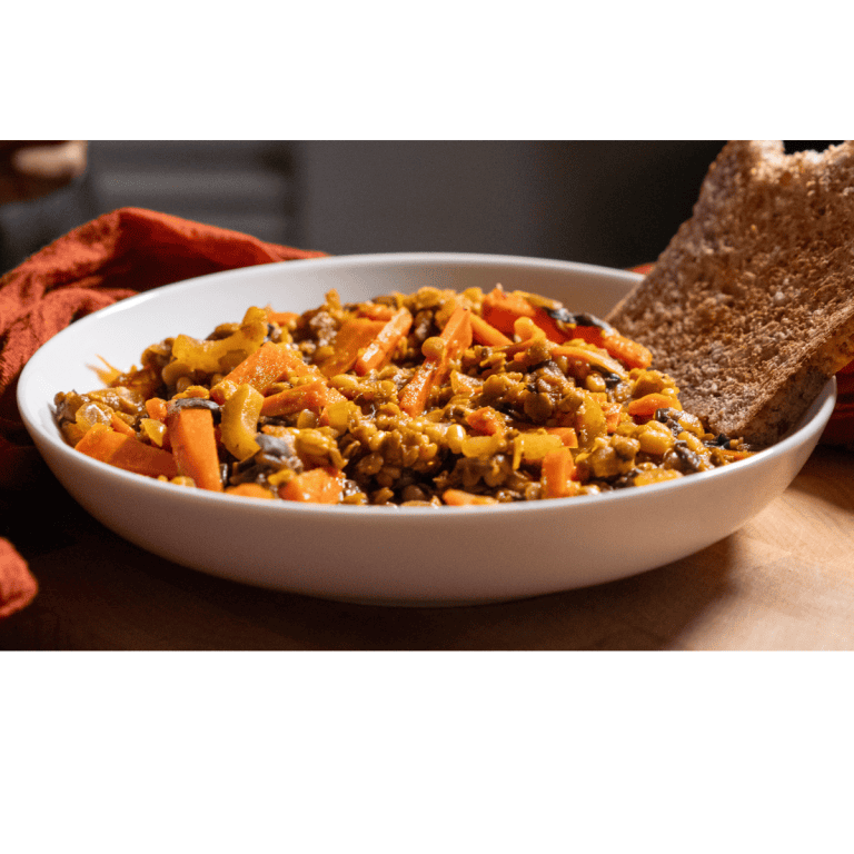 A bowl of Lentil Mung Dal Curry Soup and a slice of Ezekiel bread