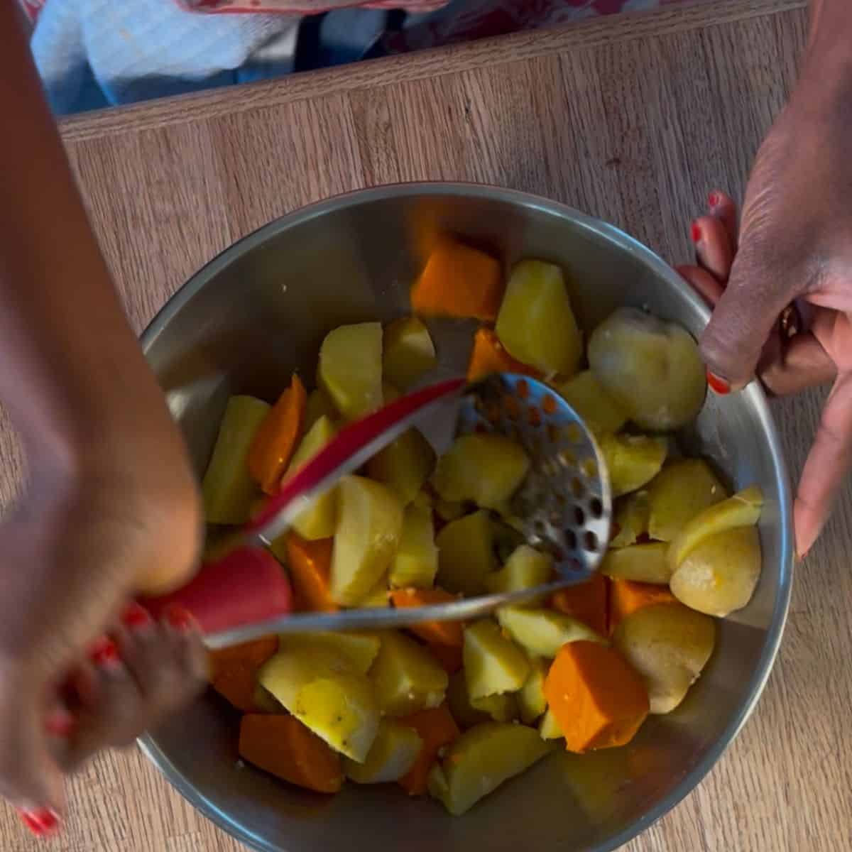 regular and sweet potatoes being mashed in a bowl