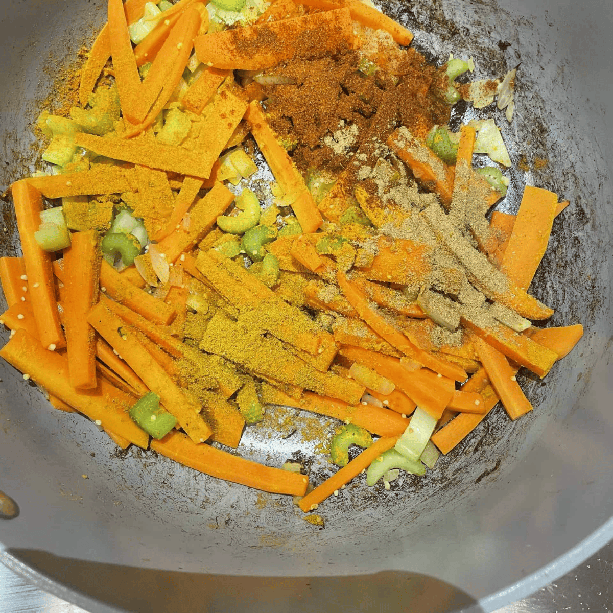 Cumin, paprika and turmeric added to the vegetables in the pot to prepare the mung dal lentil curry soup