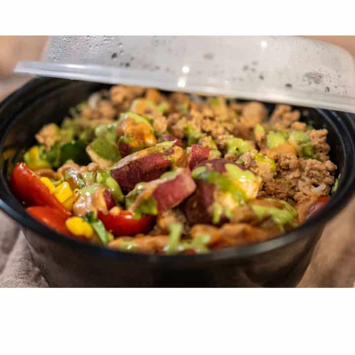 Savory teriyaki tofu rice assembled and ready to be eaten in a black container