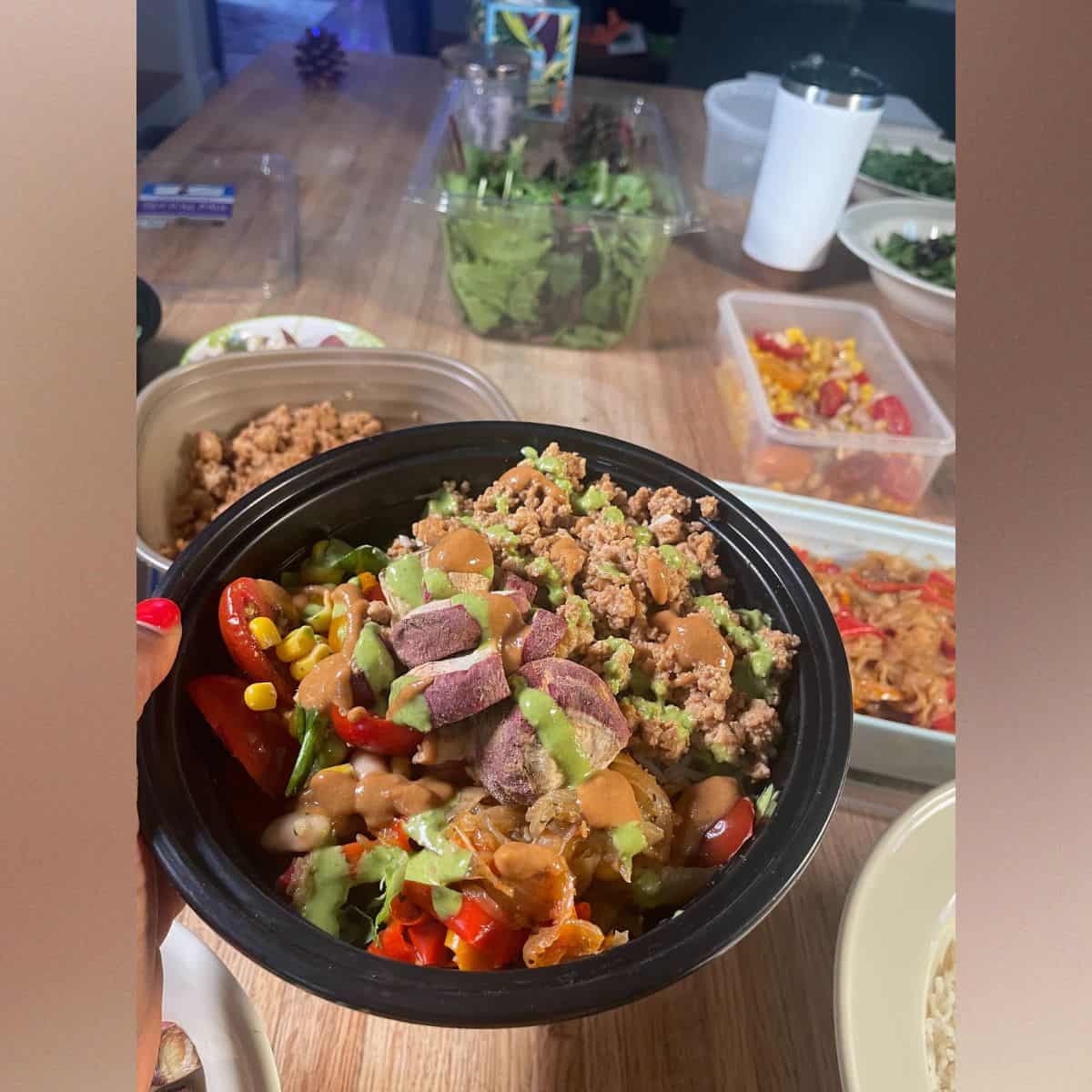 finished teriyaki tofu rice assembled in a black bowl ready to eat with on top drizzles of parley-mint dressing and dumpling sauce