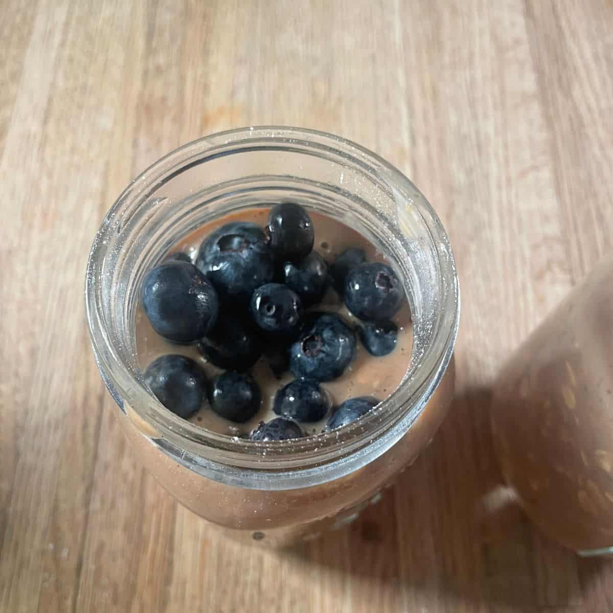 Fresh blueberries added to the mixture oatmeal in the jar