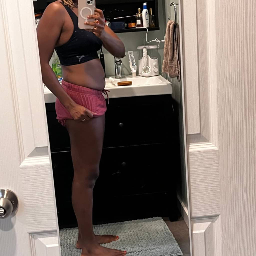 Slim woman taking mirror selfie in bathroom showing fitness and lifestyle.