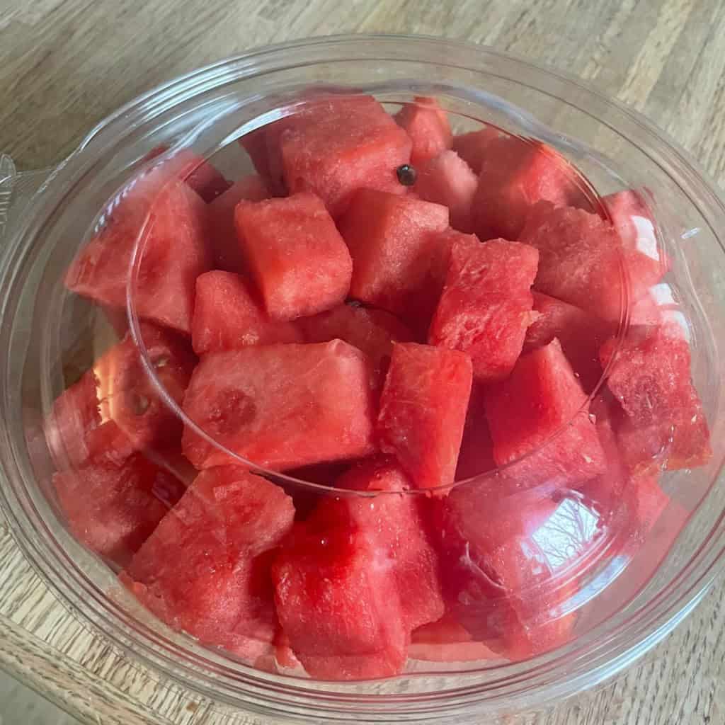 Fresh diced watermelon in a clear container for healthy snacking.