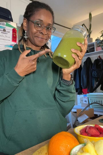 Woman holding a green smoothie in a jar, promoting digestion-friendly morning drinks.